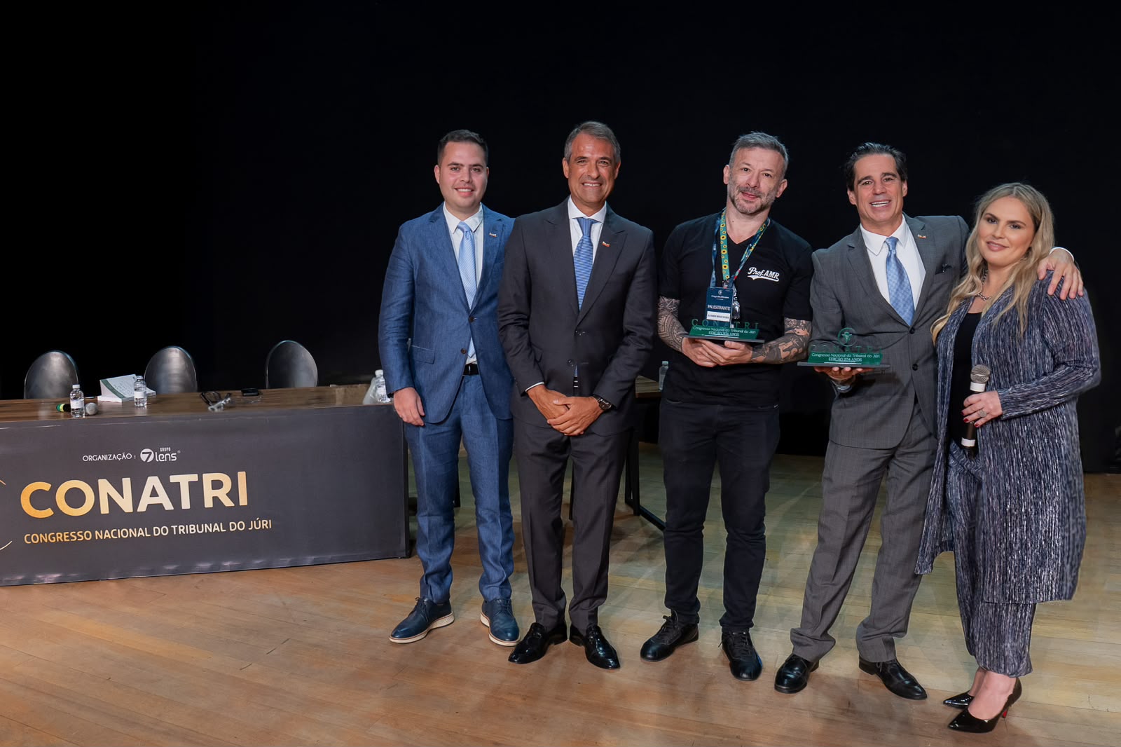 Equipe e palestrantes do CONATRI no palco, com troféus de premiação